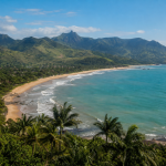 Paisagem litorânea da Serra, no Espírito Santo, com área de praia e vegetação ao fundo