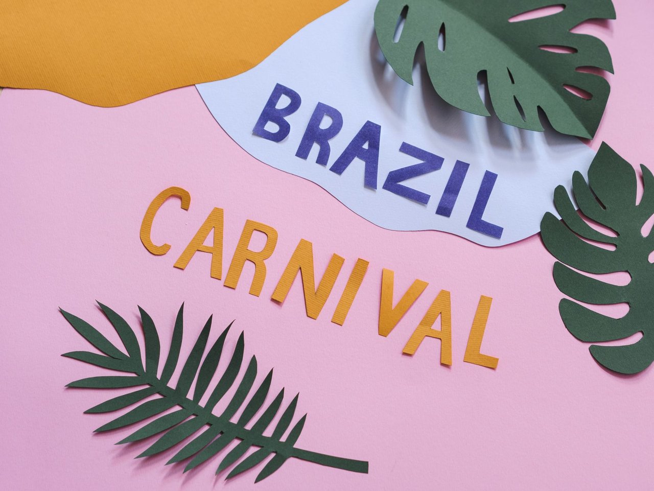 Composição de recortes de papel coloridos com folhas tropicais, representando elementos do carnaval brasileiro.