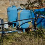 Estação industrial de tratamento de água com grandes tanques azuis e tubulações ao ar livre.