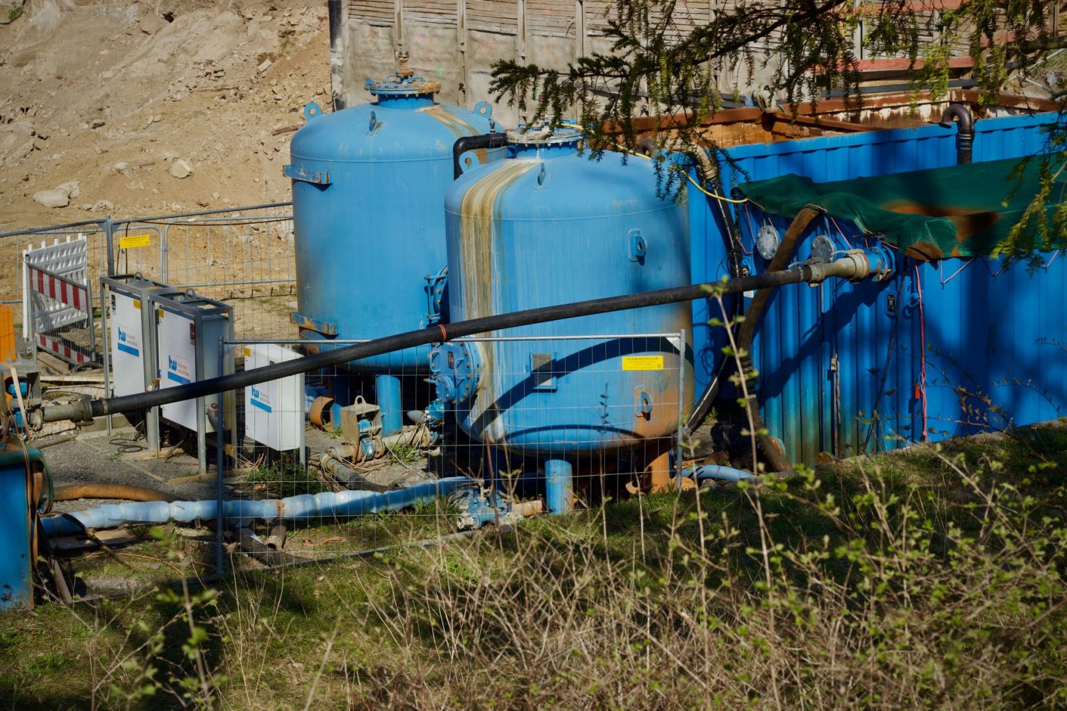 Estação industrial de tratamento de água com grandes tanques azuis e tubulações ao ar livre.